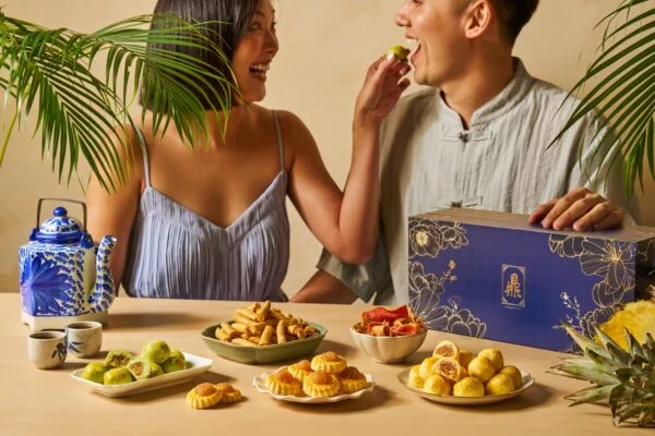 A couple sharing pineapple tarts at a table with Ding Bakery goodies.