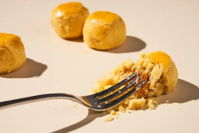 A fork breaking through pineapple pastry to reveal its crumb and filling