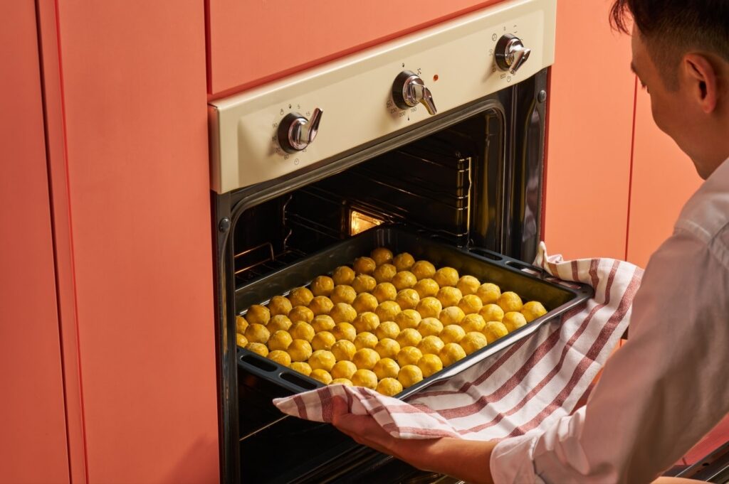A tray of pineapple balls being taken out of the oven
